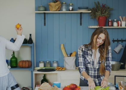 Attractive loving couple having fun in the kitchen. Handsome man juggle with fruits to impress his girlfriend at home