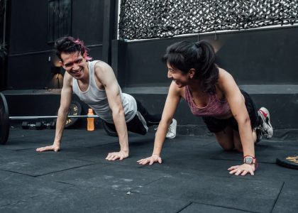 Man and woman doing pushups while smiling during a workout inside a Mexico City gym.